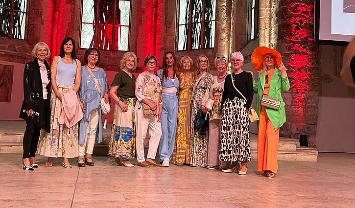 Eine Gruppe von Seniorinnen präsentiert farbenfrohe Kleidung auf der Seniorenmesse in Magdeburg