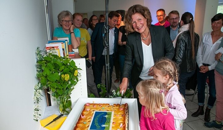 Zu sehen ist die Leiterin Annelies Plep mit 2 Kindern und Gästen im Hintergrund
