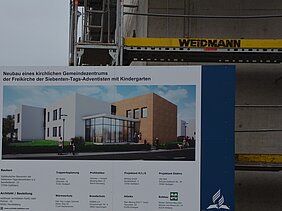 Zu sehen ist das Baustellenschild vor dem Neubau