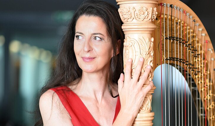 Das Bild zeigt die Harfenistin Silke Aichhorn mit ihrem Instrument