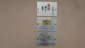 Die Bilder zeigen 3 Schilder vom Advent-Kindergarten Fürth, der durch das Land Bayern und die Stadt Fürth gefördert wird